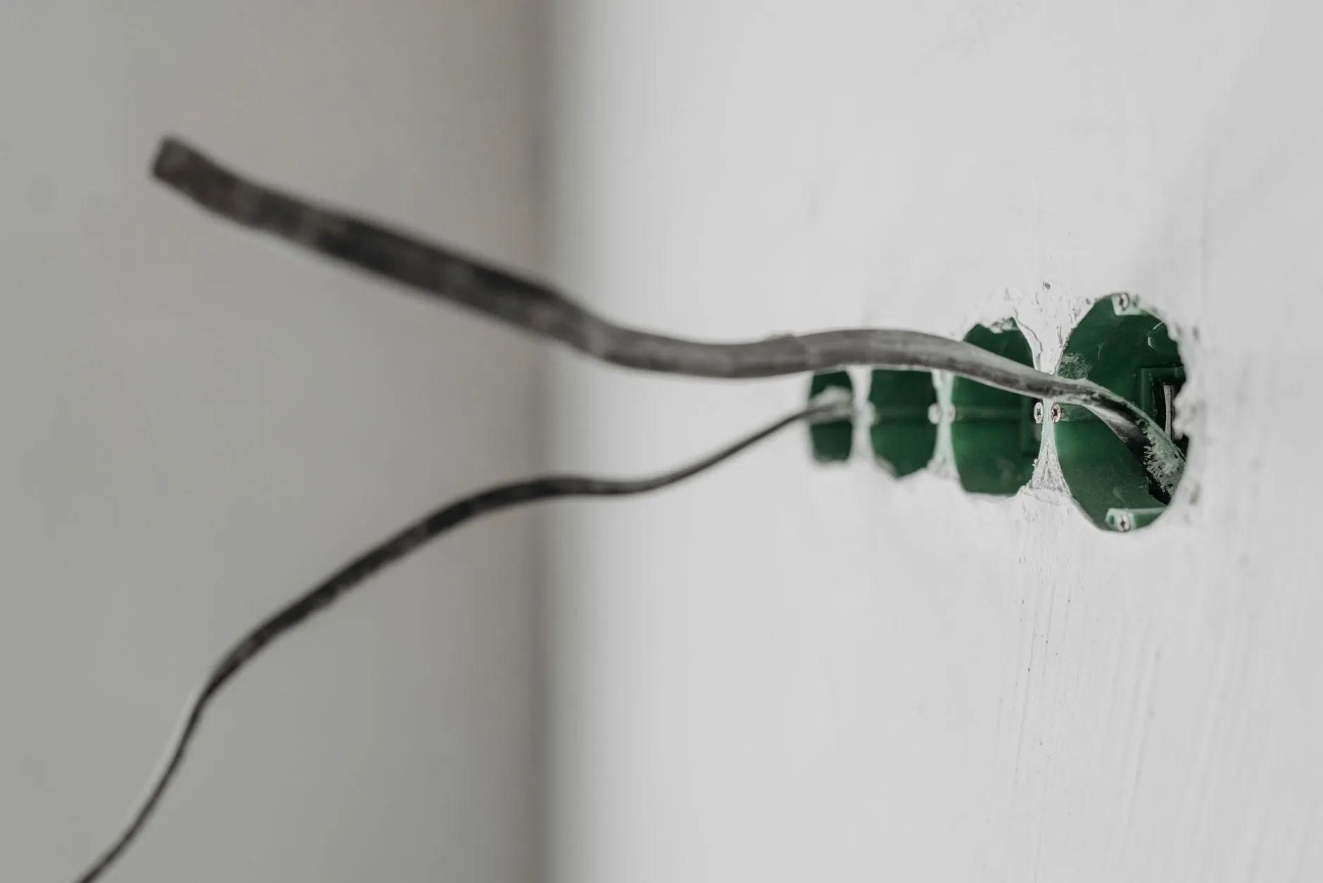 A grey cable run neatly along a white wall into a back box