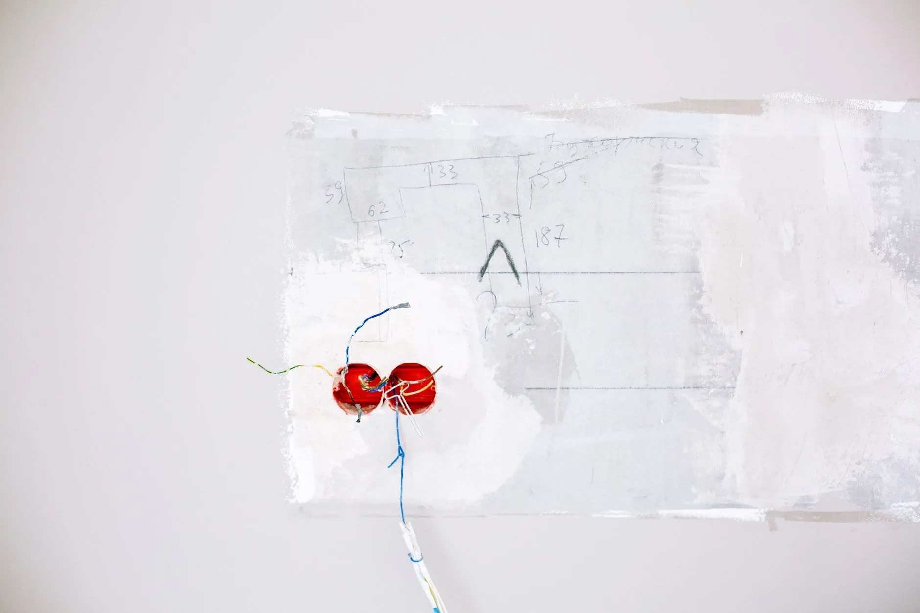 A patched wall with a pair of back boxes and a cable chase during a rewire