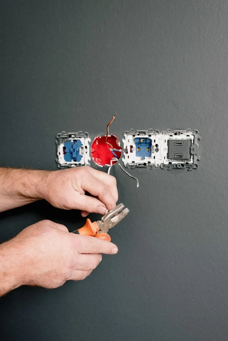 An electrician's hands preparing cable at a row of new sockets